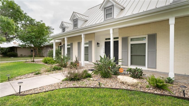 110 Amistad St, Corpus Christi, TX 78404 - view of front of house featuring a standing seam roof, covered porch, brick siding, a front yard, and metal roof