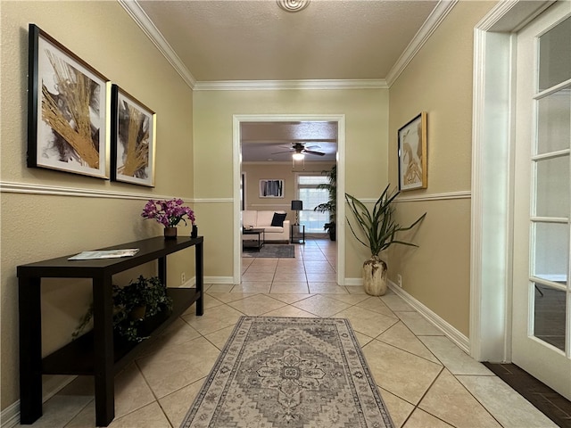 hallway with a textured ceiling, light tile patterned floors, and crown molding