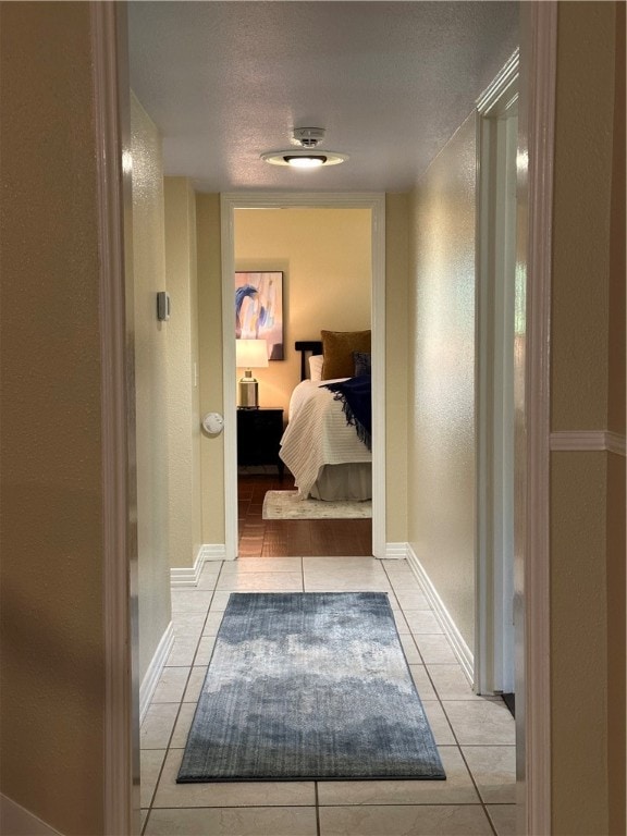 hall featuring a textured ceiling and light tile patterned flooring