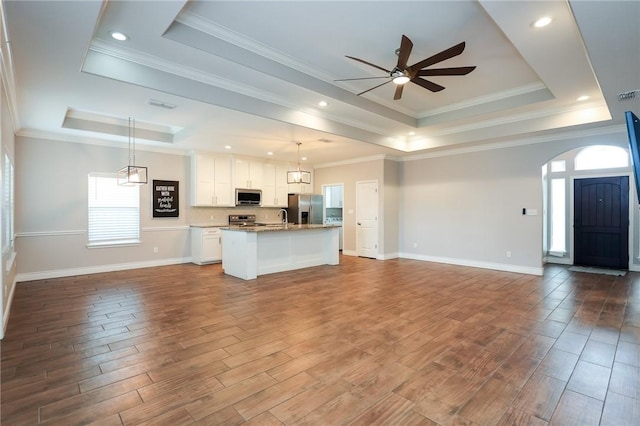 kitchen featuring pendant lighting, stainless steel appliances, a tray ceiling, and white cabinets