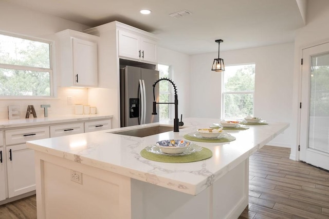 421 Anderson Dr, Alice, TX 78332 - kitchen featuring stainless steel refrigerator with ice dispenser, recessed lighting, a kitchen island with sink, white cabinetry, and wood finished floors