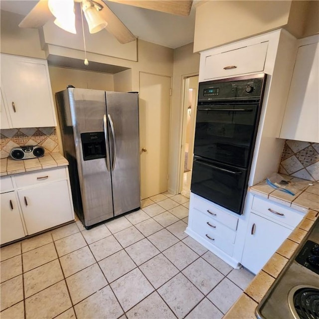 kitchen with tile countertops, stainless steel refrigerator with ice dispenser, white cabinetry, and dobule oven black