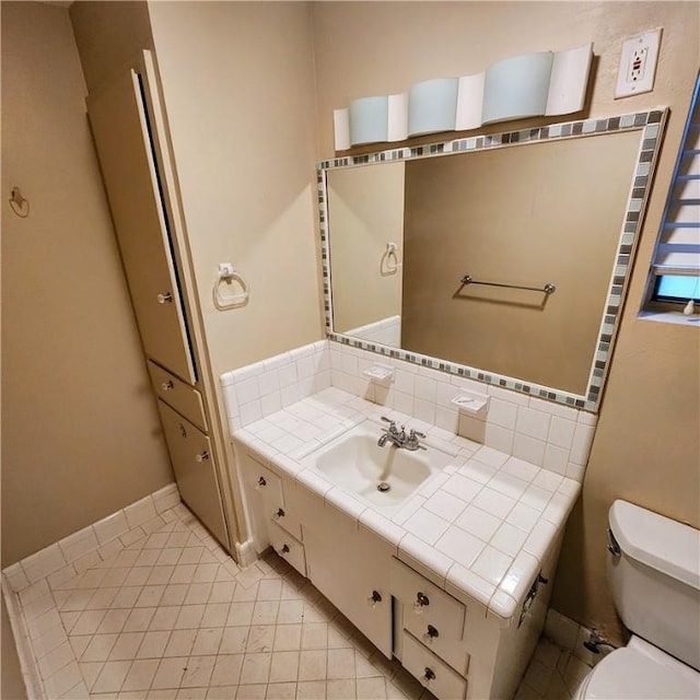 half bathroom with decorative backsplash, vanity, toilet, and tile patterned floors