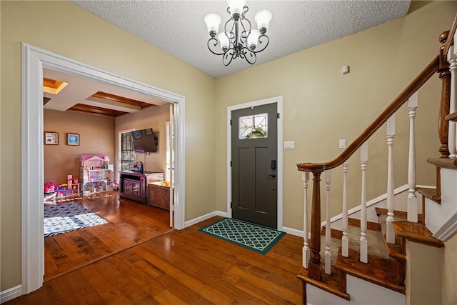 entrance foyer with hardwood / wood-style flooring, an inviting chandelier, a textured ceiling, and beamed ceiling