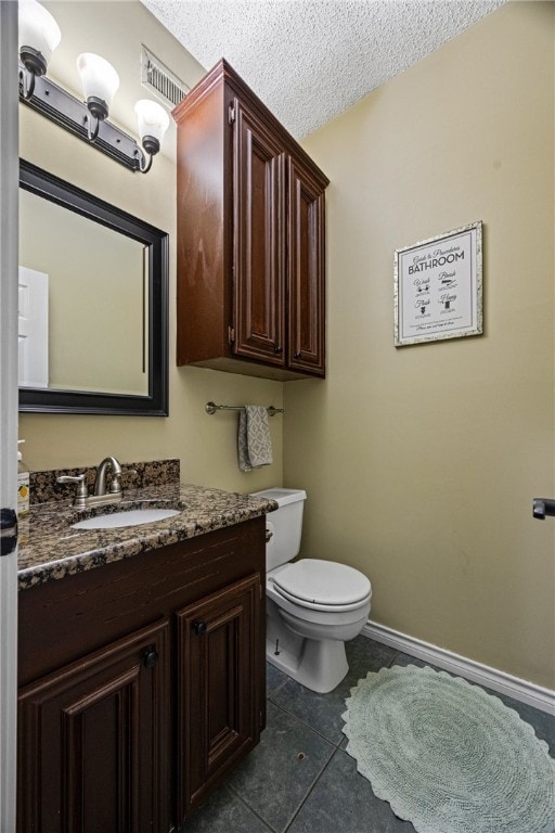 bathroom featuring vanity, tile patterned flooring, a textured ceiling, and toilet