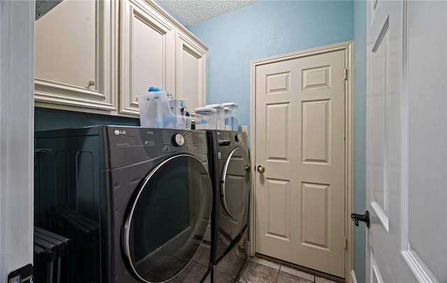 washroom with cabinets, separate washer and dryer, light tile patterned floors, and a textured ceiling