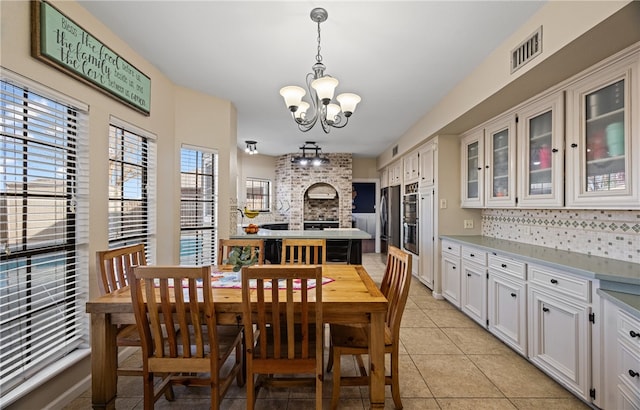 tiled dining room featuring a fireplace and a chandelier