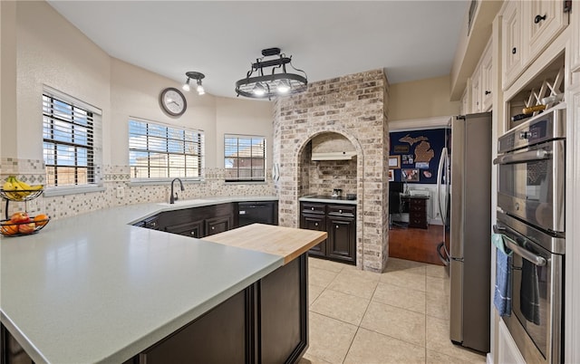 kitchen with light tile patterned flooring, black appliances, white cabinetry, dark brown cabinetry, and kitchen peninsula