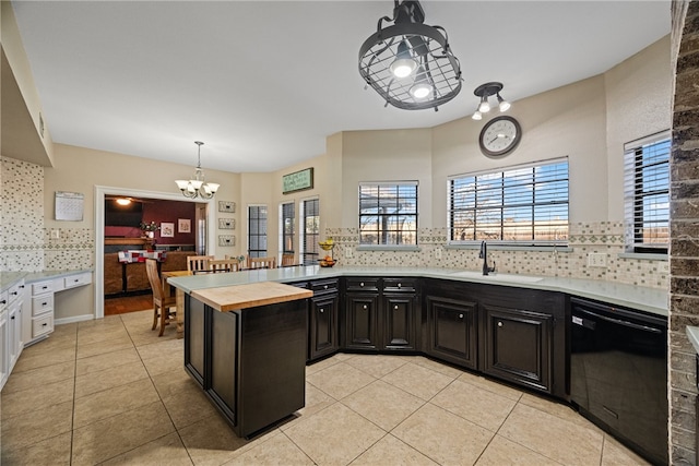 kitchen with light tile patterned flooring, sink, tasteful backsplash, hanging light fixtures, and black dishwasher