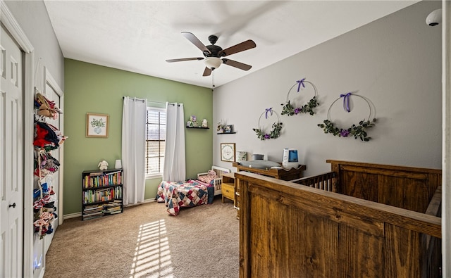 carpeted bedroom featuring a crib, ceiling fan, and a closet