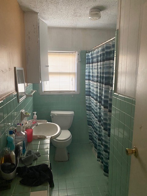 bathroom with walk in shower, tile walls, and a textured ceiling