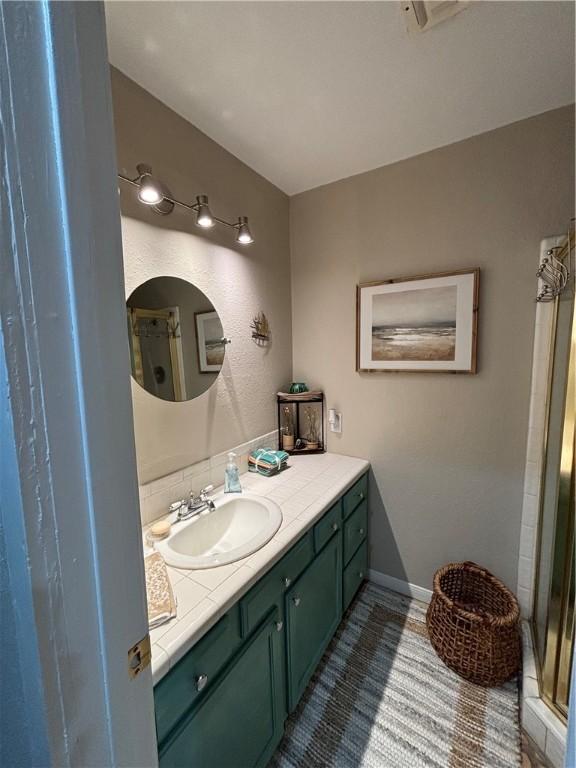 bathroom featuring a shower with shower door and vanity