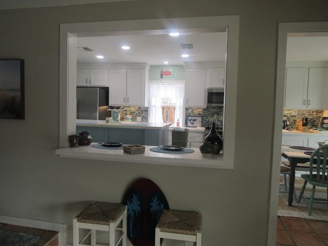 13525 Bullion Ct, Corpus Christi, TX 78418 - kitchen featuring appliances with stainless steel finishes, backsplash, white cabinetry, a kitchen bar, and recessed lighting
