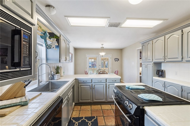 kitchen featuring sink, backsplash, black appliances, and tile counters