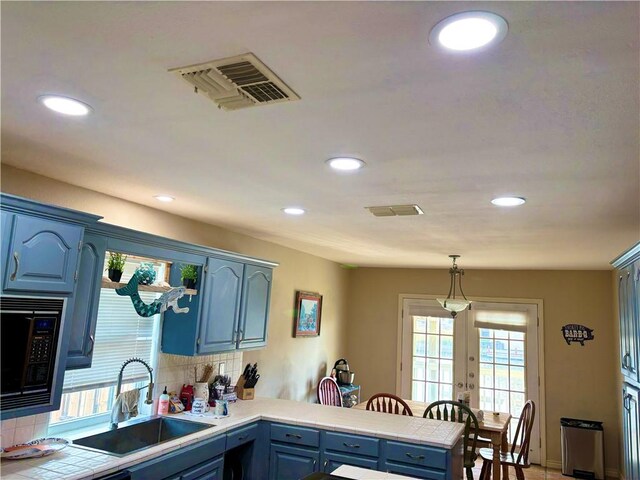 kitchen with backsplash, white refrigerator, black microwave, and kitchen peninsula