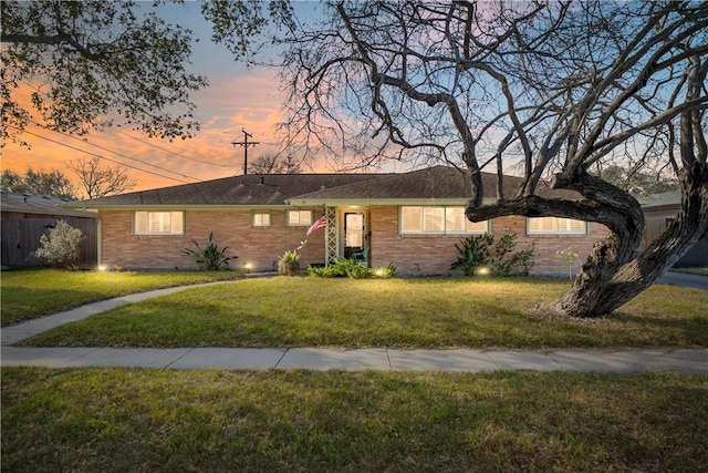 ranch-style home featuring a front lawn and brick siding