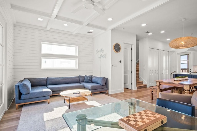 living room featuring light wood-type flooring, coffered ceiling, ceiling fan, wooden walls, and beamed ceiling