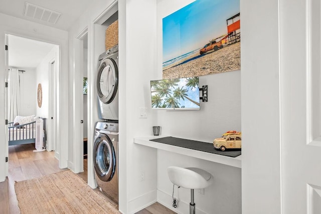 laundry area featuring light wood-type flooring and stacked washing maching and dryer