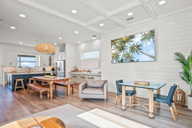 living room with beam ceiling, wooden walls, light hardwood / wood-style floors, and coffered ceiling