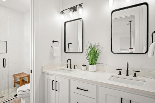 bathroom featuring a shower with door, vanity, and toilet