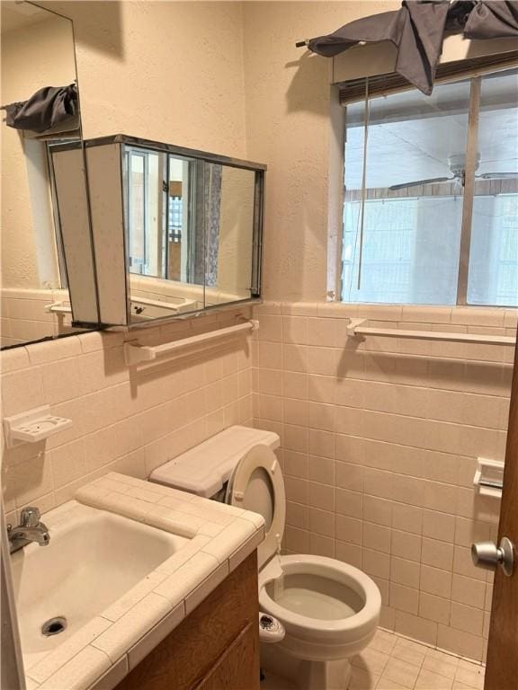 bathroom featuring tile walls, vanity, tile patterned floors, and toilet