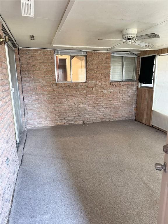 spare room with ceiling fan and brick wall