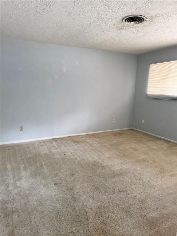 carpeted spare room with a textured ceiling