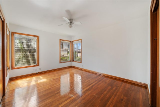 empty room featuring wood finished floors, a ceiling fan, and baseboards