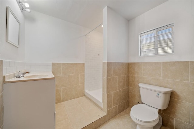 bathroom featuring toilet, a wainscoted wall, vanity, tile walls, and tiled shower