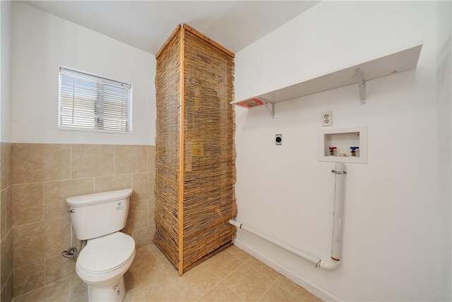 bathroom featuring toilet, wainscoting, tile walls, and tile patterned floors