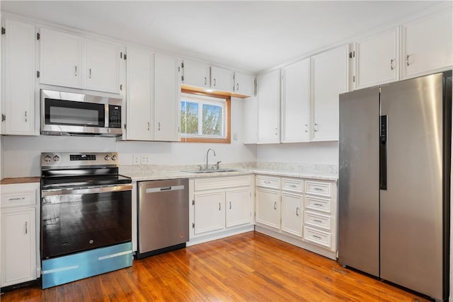 kitchen featuring appliances with stainless steel finishes, light countertops, a sink, and wood finished floors