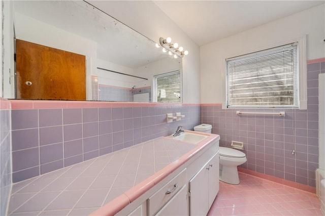 bathroom with plenty of natural light, toilet, tile patterned flooring, a tile shower, and tile walls