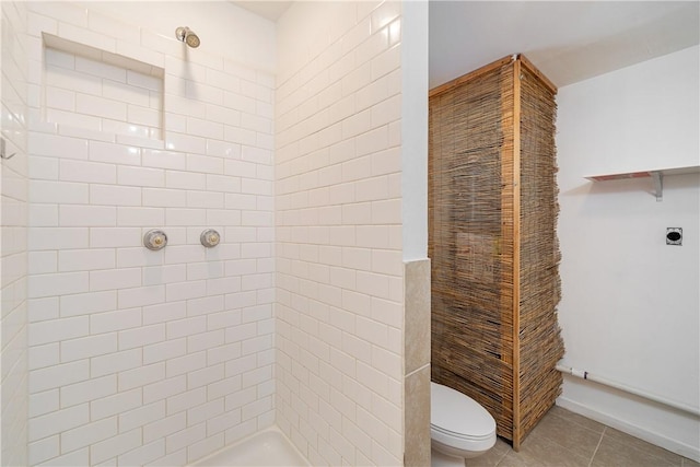 bathroom featuring toilet, tile patterned flooring, and a tile shower