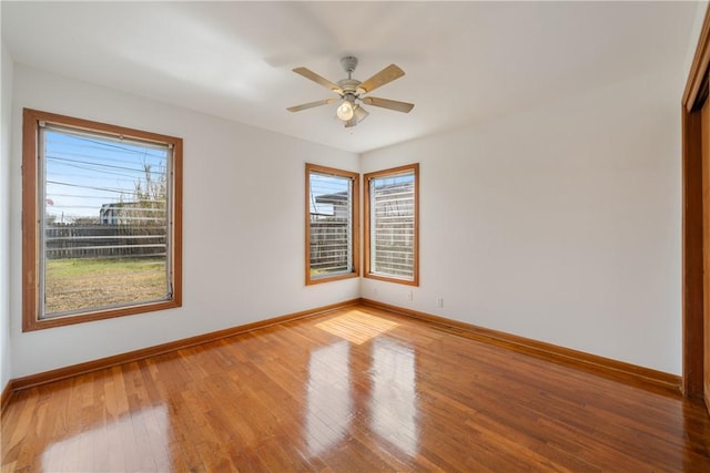 unfurnished room with ceiling fan, baseboards, and hardwood / wood-style flooring