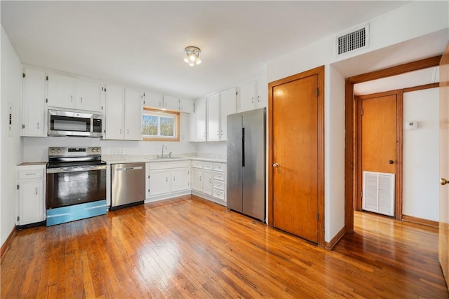 kitchen with hardwood / wood-style flooring, visible vents, stainless steel appliances, and light countertops