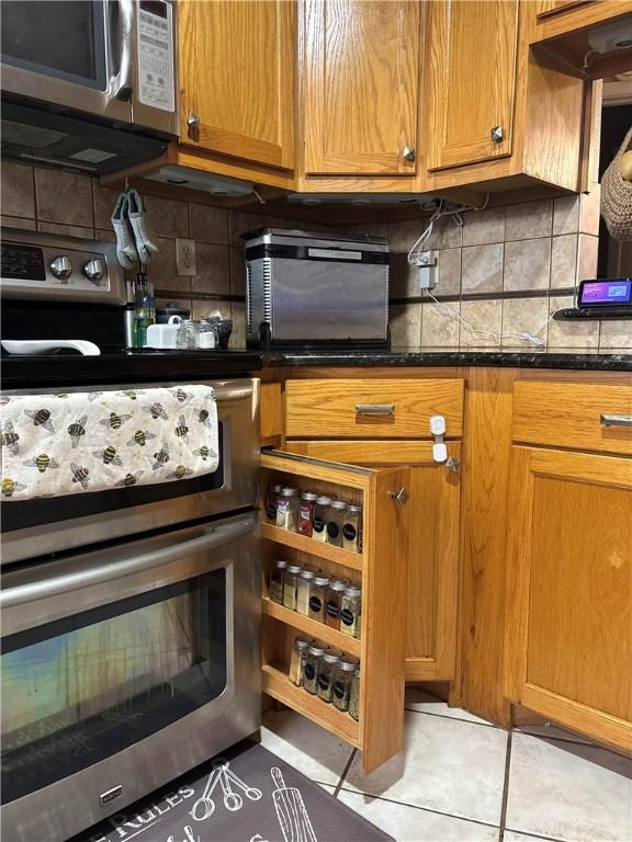 kitchen with light tile patterned floors, decorative backsplash, and dark stone counters