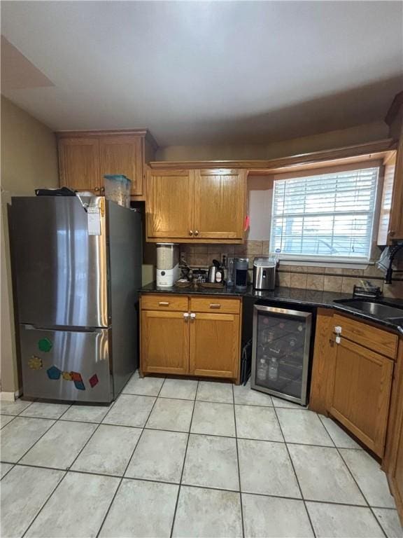 kitchen featuring sink, stainless steel refrigerator, tasteful backsplash, light tile patterned flooring, and beverage cooler