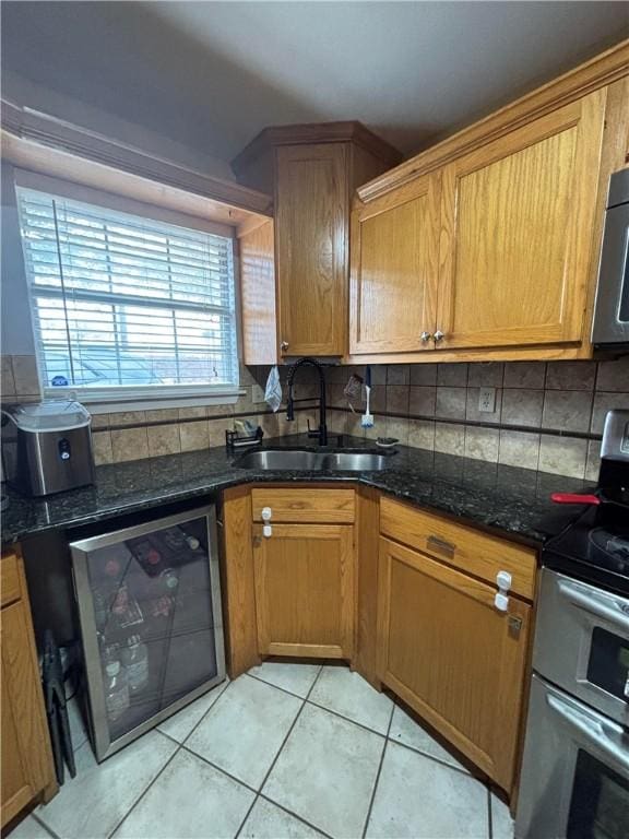 kitchen with sink, double oven range, tasteful backsplash, beverage cooler, and dark stone counters