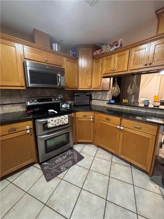 kitchen with tasteful backsplash, light tile patterned flooring, and appliances with stainless steel finishes