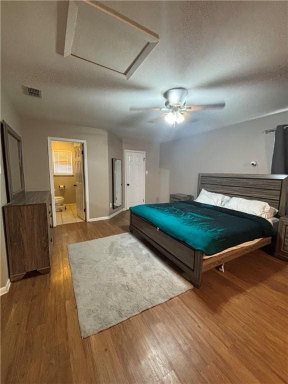 bedroom with wood-type flooring, ceiling fan, a textured ceiling, and ensuite bath