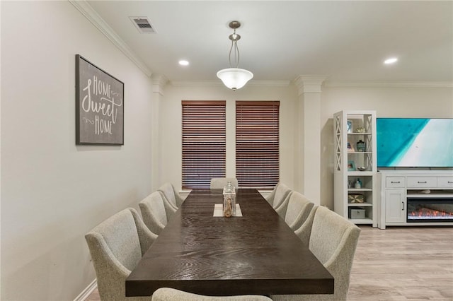 dining area with visible vents, a glass covered fireplace, crown molding, light wood-type flooring, and recessed lighting