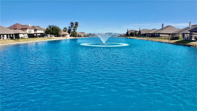 view of pool with a residential view, a water view, and fence