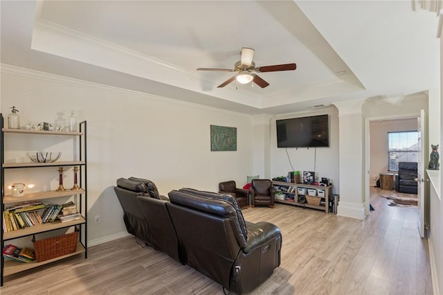 living area featuring light wood-style flooring, a tray ceiling, and crown molding