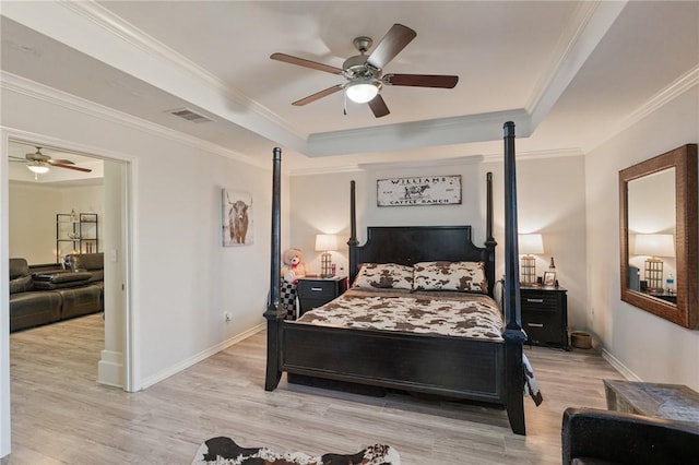 bedroom featuring a tray ceiling, visible vents, ornamental molding, wood finished floors, and baseboards