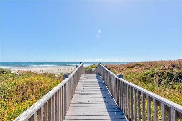 view of property's community with a water view and a beach view