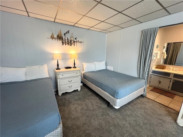 carpeted bedroom featuring a paneled ceiling and connected bathroom