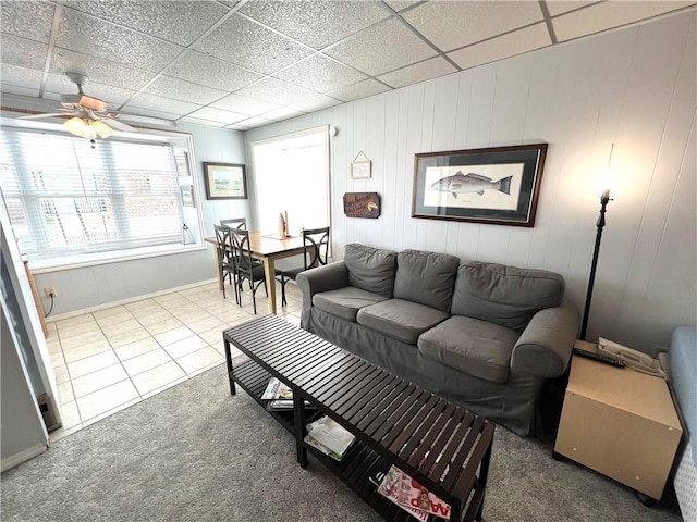 carpeted living area featuring tile patterned flooring, ceiling fan, and a drop ceiling