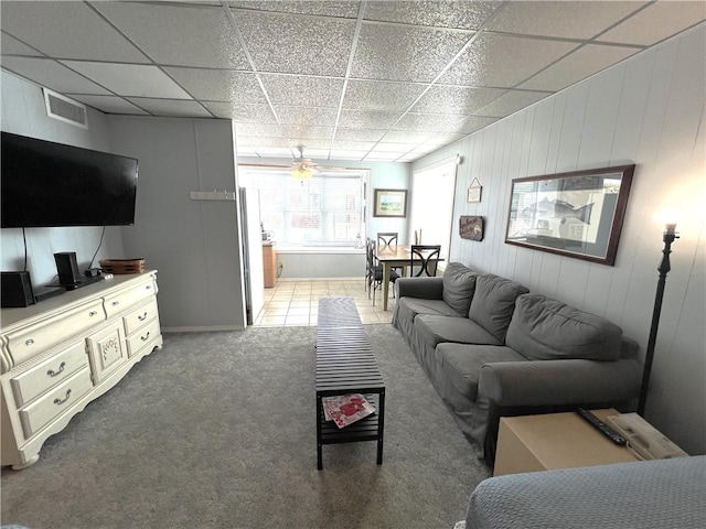 carpeted living area with tile patterned flooring, visible vents, and a drop ceiling