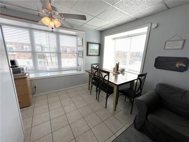 dining room featuring a ceiling fan, a paneled ceiling, and light tile patterned flooring