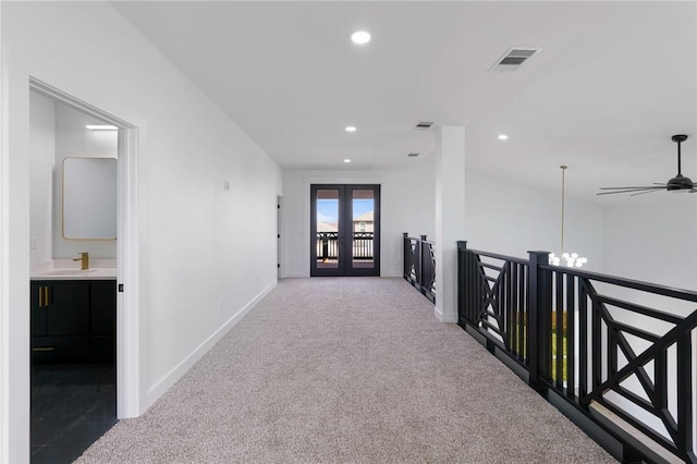 corridor featuring an inviting chandelier, carpet flooring, french doors, and sink